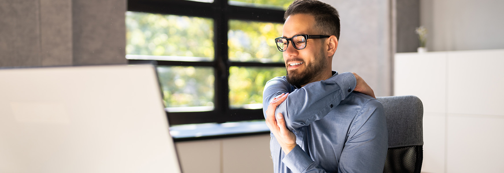 Man sitting at computer desk, stretching arms