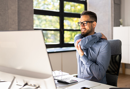 Man sitting at computer desk, stretching arms