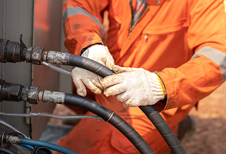 worker tending to hydraulic hoses