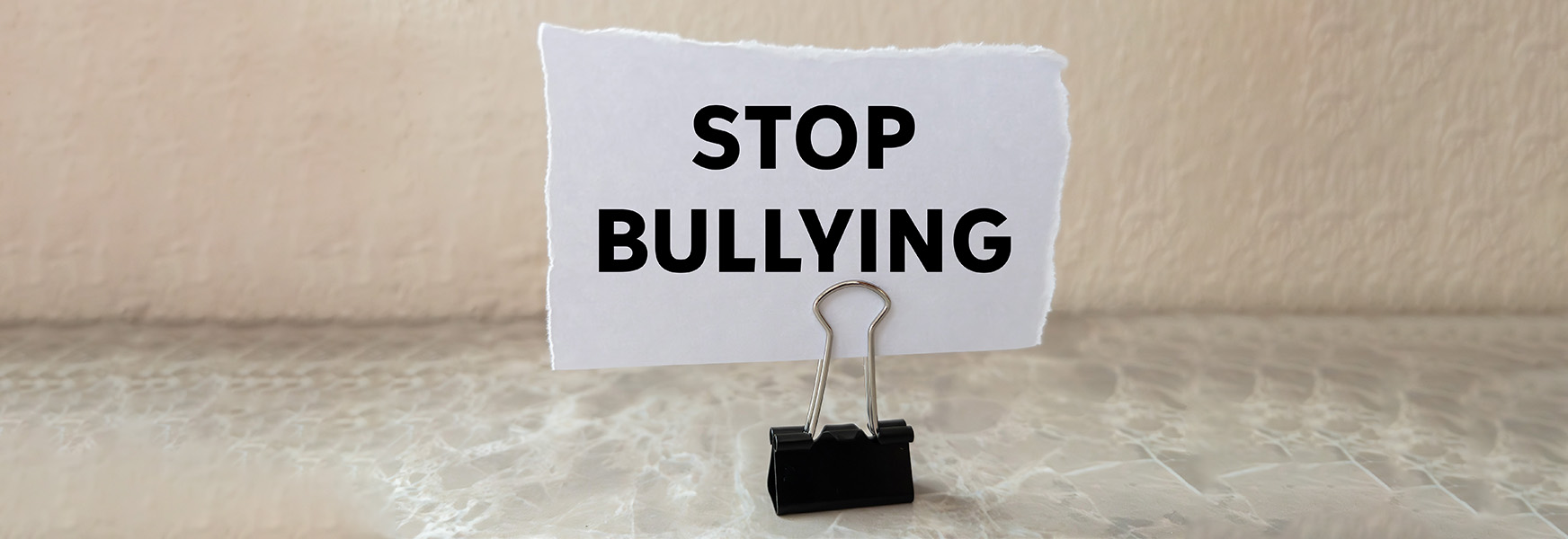 Binder clip holding a piece of paper that reads "stop bullying"