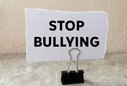 Binder clip holding a piece of paper that reads "stop bullying"