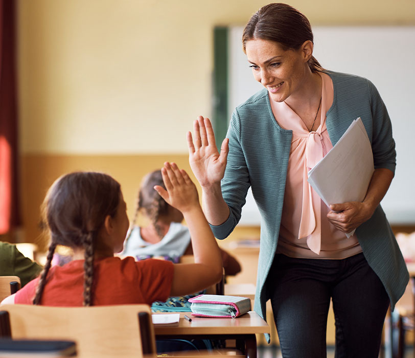 Classroom teacher and young student sharing a high-five
