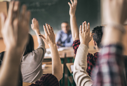 Kids in classroom raising hand