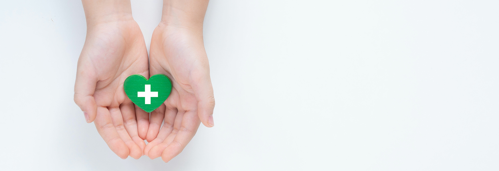 Soft focus of open hands holding wooden green heart