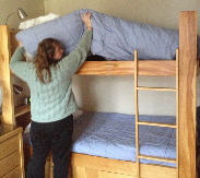 Housekeeper lifting mattress on top bunk