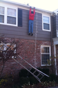 Man hanging onto the edge of a roof after his ladder falls.