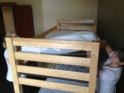 Two housekeepers making top bunk bed
